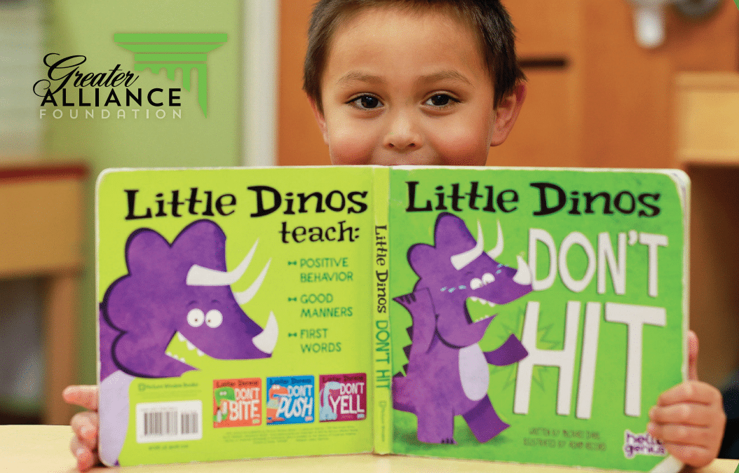 Young boy reading a Little Dinos book.